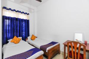 a room with two beds and a desk and a table at SPOT ON 60631 Janta Guest House in Dispur