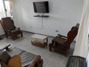 a living room with chairs and a flat screen tv at Duplex Escritores Argentinos in Rawson