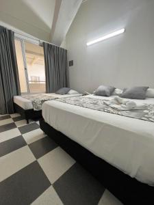 two beds in a room with a checkered floor at Hotel Boutique Santa Ana in Cartago