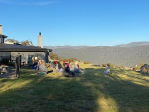 a group of people sitting in the grass near a house at Altitude 1260 in Jindabyne
