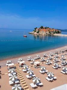 una playa con sillas y sombrillas y el océano en Hotel California by Aycon en Sveti Stefan