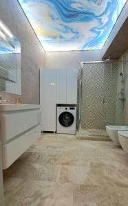 a bathroom with a sink and a washing machine at KYA Luxury in Mamaia