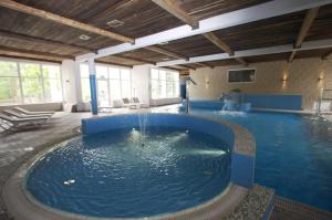 a large swimming pool in a building with a large pool at Cztery Wiatry Aparthotel in Korytnica