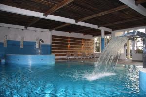 a pool with a water fountain in a building at Cztery Wiatry Aparthotel in Korytnica