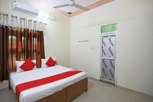 a bedroom with a bed with red pillows and a window at OYO 62761 Hotel Daksh in Mahendragarh