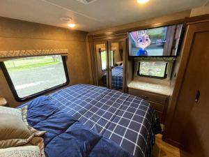 a bedroom in an rv with a bed and a tv at Quiet Country Rimrock Retreat RV in Hayden