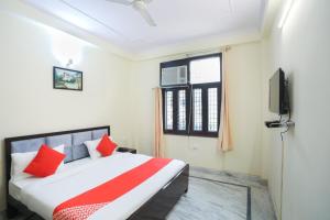 a bedroom with a bed with red pillows and a window at OYO Golden Suites in Ghaziabad
