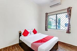Schlafzimmer mit einem Bett mit roten Kissen und einem Fenster in der Unterkunft OYO Shree Balaji Lodging in Chikalthān