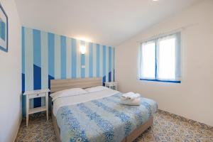 Schlafzimmer mit einem Bett mit blauen und weißen Streifen in der Unterkunft Villaggio Residence Nettuno in Massa Lubrense