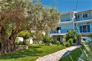 a villa with a tree in front of a building at Zois Apartments in Nikiana