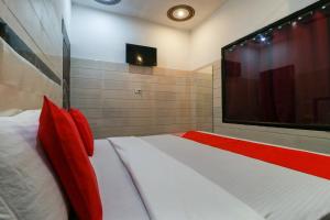 a bedroom with a bed with red pillows and a flat screen tv at OYO 65320 Hotel Surya in Sāmāna