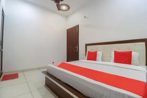 a bedroom with a large bed with red pillows at OYO 65320 Hotel Surya in Sāmāna