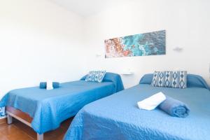2 Betten in einem Zimmer mit blauer Bettwäsche in der Unterkunft Apartments Residencial Cala Ferrera in Cala Ferrera