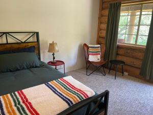 1 dormitorio con 1 cama, 1 silla y 1 ventana en Bear Creek Cabins en Midpines