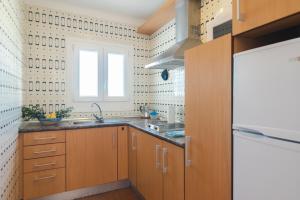 una cocina con armarios de madera y una ventana en Apartments Residencial Cala Ferrera, en Cala Ferrera