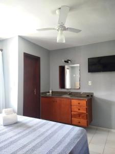a bedroom with a ceiling fan and a dresser with a mirror at Residencial Mont Sinai Tonziro -Taperapuan in Porto Seguro