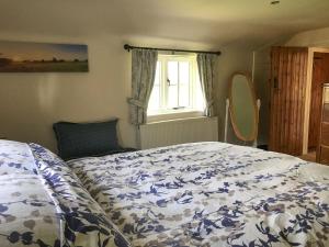 a bedroom with a bed with a blue and white comforter at Garden Cottage in Tetford