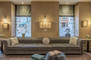 a living room with a couch and three windows at Hotel Litteraire Le Swann, BW Premier Collection in Paris