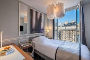 a room with a bed and a table and a window at Hotel Litteraire Le Swann, BW Premier Collection in Paris