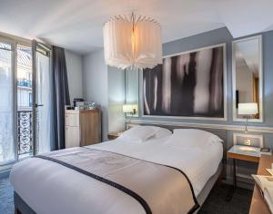 a bedroom with a large white bed and a chandelier at Hotel Litteraire Le Swann, BW Premier Collection in Paris