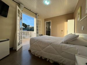 a bedroom with a large bed and a balcony at Hotel Solar da Montanha in Campos do Jordão
