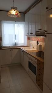 eine Küche mit weißen Schränken, einem Waschbecken und einem Fenster in der Unterkunft Acogedor apartamento a pie de playa in Nigrán