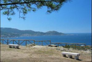 dos bancos sentados en una colina con vistas al agua en Acogedor apartamento a pie de playa, en Nigrán