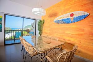 a dining room with a table and a surfboard on the wall at Jaco Bay 6701 - Maikol Arias in Jacó
