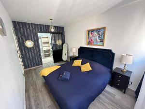 Un dormitorio con una gran cama azul con almohadas amarillas en SPACIEUX DUPLEX PRES DES QUAIS DE SEINE LINGE MAISON TOUT FOURNI PARKING GRATUIT bienvenue en Ruan