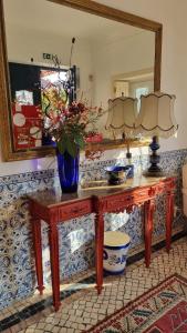 una mesa con un jarrón en ella con un espejo en Casa Da Palmeira en Leiria