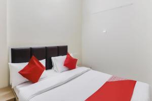 Una cama con almohadas rojas y blancas. en OYO Zion Inn, en Vapi