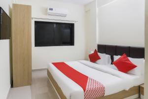 Schlafzimmer mit einem Bett mit roten Kissen und einem TV in der Unterkunft OYO Zion Inn in Vapi
