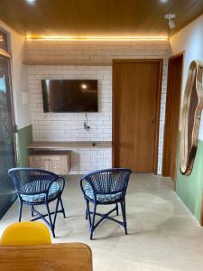 2 blaue Stühle und ein TV in einem Zimmer in der Unterkunft CHALEVILLE Coqueiro 46 in Luis Correia
