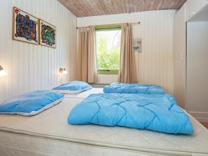 two beds in a bedroom with blue pillows at 6 person holiday home in R nde in Rønde