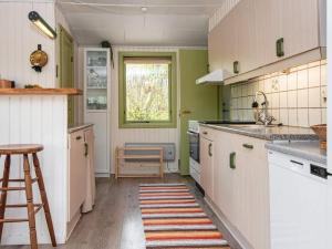 kuchnia z białymi szafkami, oknem i stołkiem w obiekcie 6 person holiday home in R nde w mieście Rønde