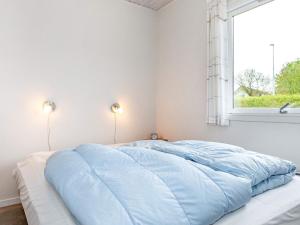 Un dormitorio con una gran cama azul y una ventana en Holiday Home Toftholmvej, en Vester Torup