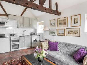 sala de estar con sofá y cocina en Old Rectory Cottage en Fernhurst