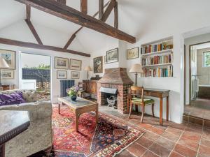 a living room with a fireplace and a couch and a table at Old Rectory Cottage in Fernhurst