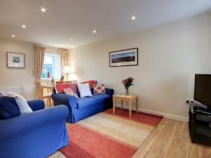 a living room with a blue couch and a tv at Kestrel Cottage - 27937 in Cambusbarron