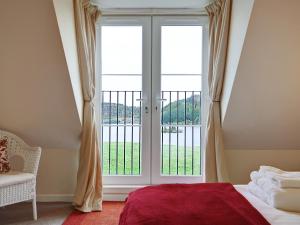 a bedroom with a bed and a large window at Kestrel Cottage - 27937 in Cambusbarron