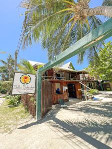 a sign for a resort on a beach with a palm tree at Bella's Backpackers Hostel in Caye Caulker