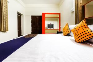 a bedroom with a large bed with orange and blue pillows at Hotel O Tirupati Guest House in Gwalior
