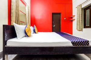 a bed in a room with a red wall at SPOT ON 66976 Tirupati Guest House in Gwalior