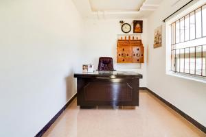 een bureau in een kamer met een klok aan de muur bij OYO 68320 Bgr Residency in Tirupati