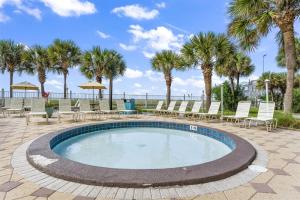 a swimming pool with chairs and palm trees at The Summit 702 in Panama City Beach