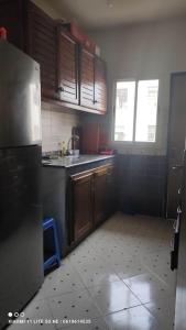 a kitchen with a stainless steel refrigerator and wooden cabinets at شقة من غرفتين نوم وصالة in Tangier