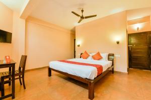 1 dormitorio con cama, escritorio y ventilador de techo en OYO 13415 Cherai Village Home Stay en Cherai Beach