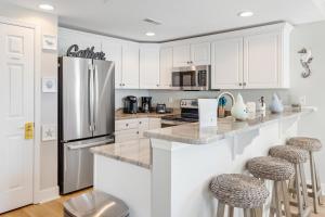 a kitchen with white cabinets and a stainless steel refrigerator at Sunset Bay I 306 in Ocean City