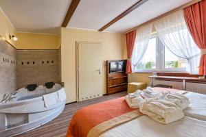 1 dormitorio con 1 cama con bañera y lavamanos en Sommer Residence Hotel&Spa en Kluczbork