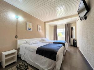 a bedroom with two beds and a flat screen tv at Hotel Solar da Montanha in Campos do Jordão